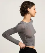 Blusa de manga larga confeccionada en tejido rib con textura acanalada y leve transparencia. Presenta un corte ajustado al cuerpo y escote redondo.