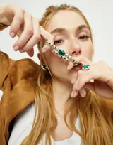 Pulsera elástica de bolas plateadas con un cristal facetado verde.