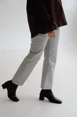 Pantalón cropped de tiro medio con acabado engomado, corte recto y bolsillos laterales. Presenta cierre frontal con botón y costuras a tono.