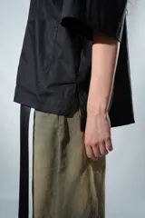 Camisa negra de manga corta con cierre frontal y cuello clásico.