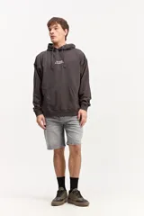 Canguro de algodón con efecto lavado de corte oversize, capucha con cordones ajustables, bolsillo canguro delantero y estampa frontal con texto en el pecho.