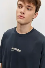 Remera oversize gris oscuro, de manga corta y cuello redondo, con pequeño estampado frontal con la palabra 'DISCOGRAPHY'.