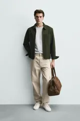 Pantalón jeans de corte recto y tiro medio, confeccionado en denim de algodón color beige con efecto lavado, bolsillos clásicos y cierre frontal con cremallera y botón.