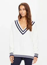 Sweater de punto color blanco con escote en V profundo y rayas azul marino en cuello, puños y dobladillo.