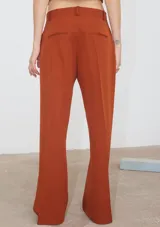 Pantalón de corte recto confeccionado en tela sastrera color ladrillo, con tajo lateral en la botamanga y bolsillos laterales.