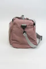 Bolso deportivo color rosa con detalles en beige y gris. Tiene doble asa de mano y correa de hombro ajustable. Cuenta con dos bolsillos frontales con cierre y logo de la marca en la esquina inferior derecha.