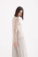 Blusa de encaje color beige, de manga larga y corte recto, con diseño floral detallado.