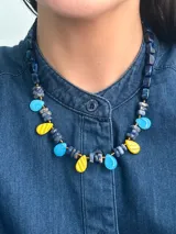 Collar corto con diseño multicolor compuesto por cuentas de cristal checo, piedras naturales y piezas de acrílico en tonos azul, celeste y amarillo, con cierre de cadena de acero quirúrgico.