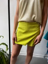 Short pollera color lima, confeccionado en crepé con spandex, con diseño cruzado en el frente.