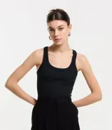 Musculosa básica de calce ajustado confeccionada en tejido rib acanalado. Presenta escote redondo y breteles medios, ofreciendo un diseño versátil y cómodo.