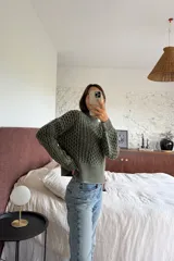 Sweater de tejido de punto con diseño de ochos en relieve, color gris oscuro con detalles en negro. Presenta cuello redondo alto y puños y ruedo acanalados.