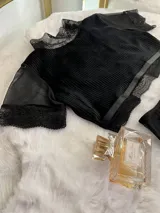 Conjunto de lencería compuesto por un top de cuello alto con mangas cortas y una bombacha de tiro alto. Ambas piezas combinan paneles de terciopelo, microtul transparente y detalles de encaje elastizado.