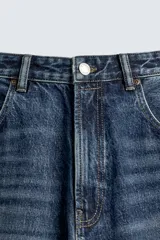 Jeans de denim de algodón, color azul oscuro con efecto lavado. Presentan un corte muy holgado (baggy fit) en toda la pierna y tiro medio. Tienen cinco bolsillos y cierre frontal con cremallera y botón.