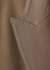 Blazer de corte recto y diseño estructurado, confeccionado en tejido mezcla de lana color marrón. Presenta cierre de doble botonadura, cuello con solapas de muesca, bolsillos de solapa en el frente y bolsillo de ribete en el pecho. Incluye forro interior y mangas largas con puños abotonados.