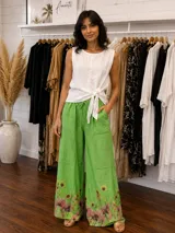 Pantalón amplio de lino color verde con estampado botánico de flores en el ruedo, cintura elastizada con cordón ajustable y bolsillos laterales.