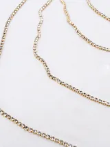 Collar de tres niveles con cadenas finas de strass engarzado en metal dorado.