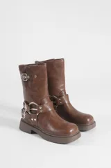 Botas de caña media color marrón, elaboradas en cuero vegano, con diseño estilo biker, taco bajo, hebillas metálicas decorativas y argollas laterales.