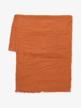 Bufanda lisa color naranja, con flecos pequeños en los extremos.