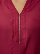 Blusa de satén color azul, con cuello camisero y cierre frontal parcial con cremallera. Presenta mangas largas con puños abotonados y un corte recto y fluido.