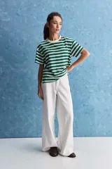 Remera de corte holgado con diseño a rayas horizontales en color verde y blanco, cuello redondo y mangas cortas con vuelta.