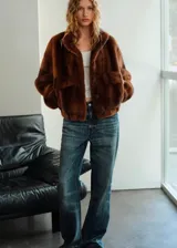 Chaqueta de efecto pelo en color marrón, de corte recto, con cuello alto, mangas largas con puños elásticos y cierre delantero con botones. Cuenta con dos bolsillos de solapa en la parte frontal.