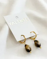 Par de aros dorados tipo argolla con dije colgante de piedra veteada en tonos marrones y cuentas doradas. Cierre a presión.