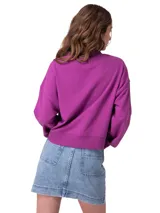 Buzo de cuello redondo color fucsia, confeccionado en french terry suave. Presenta un gráfico iridiscente con el nombre de la marca en el centro del pecho, mangas largas con hombros caídos y puños, cuello y dobladillo de punto acanalado.