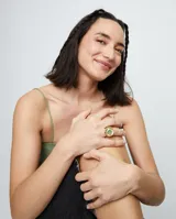 Anillo tipo sello dorado con forma de ojo y cristal facetado verde en el centro.