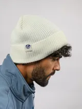 Gorro tipo beanie de tejido acanalado en color blanco, con dobladillo y etiqueta lateral con el logo de Umbro.