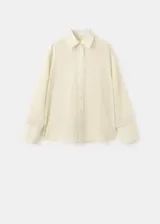 Camisa oversize color beige con sutiles rayas verticales, cuello camisero y cierre frontal con botones.
