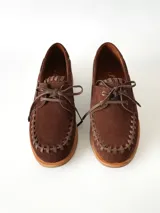 Sandalias de cuero gamuzado color marrón chocolate, diseño tipo huarache con tiras entrelazadas, tira en el empeine, talón cerrado y hebilla metálica de ajuste lateral.