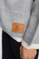 Buzo oversize de tejido de punto con diseño jacquard en mangas y espalda, cuello redondo y detalle de etiqueta de cuero sintético en el ruedo.