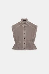 Chaleco de denim con cuello subido y manga sisa. Presenta cintura elástica con frunces laterales, cierre frontal con botones a presión y cremallera oculta.