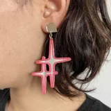 Aros colgantes con base cuadrada negra y dije con forma de estrella negra con interior dorado.