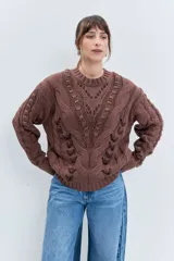 Sweater de punto color celeste, con diseño de trenzas y detalles de cordones entrelazados en el frente y las mangas. Presenta cuello redondo y puños acanalados.