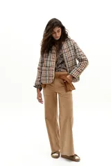 Chaqueta reversible con un lado de twill de lana a cuadros en tonos beige, marrón y gris, con vivos en pana color camel y bolsillos frontales. El otro lado es de algodón capitoneado con estampado de arabescos. Tiene cuello a la base y botones metálicos a presión escondidos.