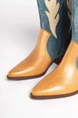 Bota estilo texana de gamuza color marrón, con diseño de apliques en forma de llamas en color crema y taco de madera.