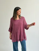 Sweater Ginebra de punto color magenta, con escote redondo, mangas largas con presilla y botón para ajustar, y diseño holgado con bajo asimétrico.