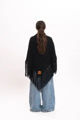 Triángulo tejido artesanalmente en telar manual con hilado mecha de lana merino, de color negro, con diseño envolvente y flecos largos en los bordes.
