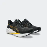 Championes de running Asics Versablast 4, color negro con detalles en naranja y suela blanca con tecnología AmpliFoam+. Diseño ligero y reactivo para entrenamiento versátil.