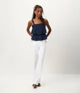 Blusa femenina color azul marino, sin mangas, con breteles anchos que tienen nudos decorativos y escote recto. Presenta capas sobrepuestas en la parte delantera que crean un leve volumen.