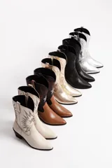 Botas tejanas doradas de cuero vacuno, con forro de neoprene, taco de 4 cm y cierre lateral.