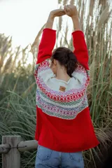 Sweater rojo de lana merino con cuello redondo y mangas largas. Presenta un canesú con diseño geométrico multicolor en tonos blanco, rojo, azul, verde y rosa.