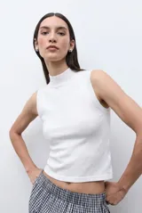 Top sin mangas de tejido canalé en color blanco, con cuello alto tipo tortuga y ajuste al cuerpo.