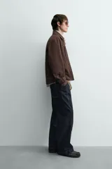 Sobrecamisa de corte regular confeccionada en tejido con estructura canvas color marrón. Presenta un ligero acolchado interior, cuello de solapa y cierre frontal con cremallera metálica. Incluye dos bolsillos de plastrón en el pecho y bolsillos laterales de vivo, con mangas largas terminadas en puños con botón.