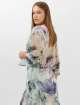Conjunto compuesto por un vestido midi de gasa con estampado floral en tonos violeta, azul y crema, con escote en V, tirantes anchos y ruedo asimétrico con volados. Incluye una chaqueta corta tipo torera de mangas 3/4 confeccionada en la misma tela. Posee forro interno a tono.