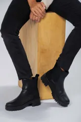 Bota tipo chelsea de cuero negro con elásticos laterales y suela track de goma.