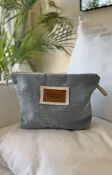 Nécessaire gris con textura tejida y parche de cuero con el logo de la marca McK Ocean.