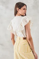 Blusa sin mangas color crema con bordado floral, cuello mao y volados en los hombros.
