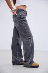 Jean de tiro medio en color negro lavado, con corte recto y amplio. Presenta detalles de tachas metálicas a lo largo de las costuras laterales y en la zona de los bolsillos delanteros.